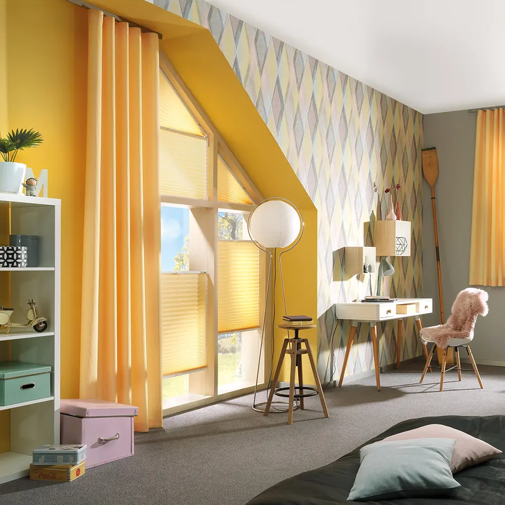Helles, modern eingerichtetes Zimmer mit gelben Vorhängen und Plissees an einem großen, dreieckigen Fenster, farbenfroher Tapete und Schreibtisch.